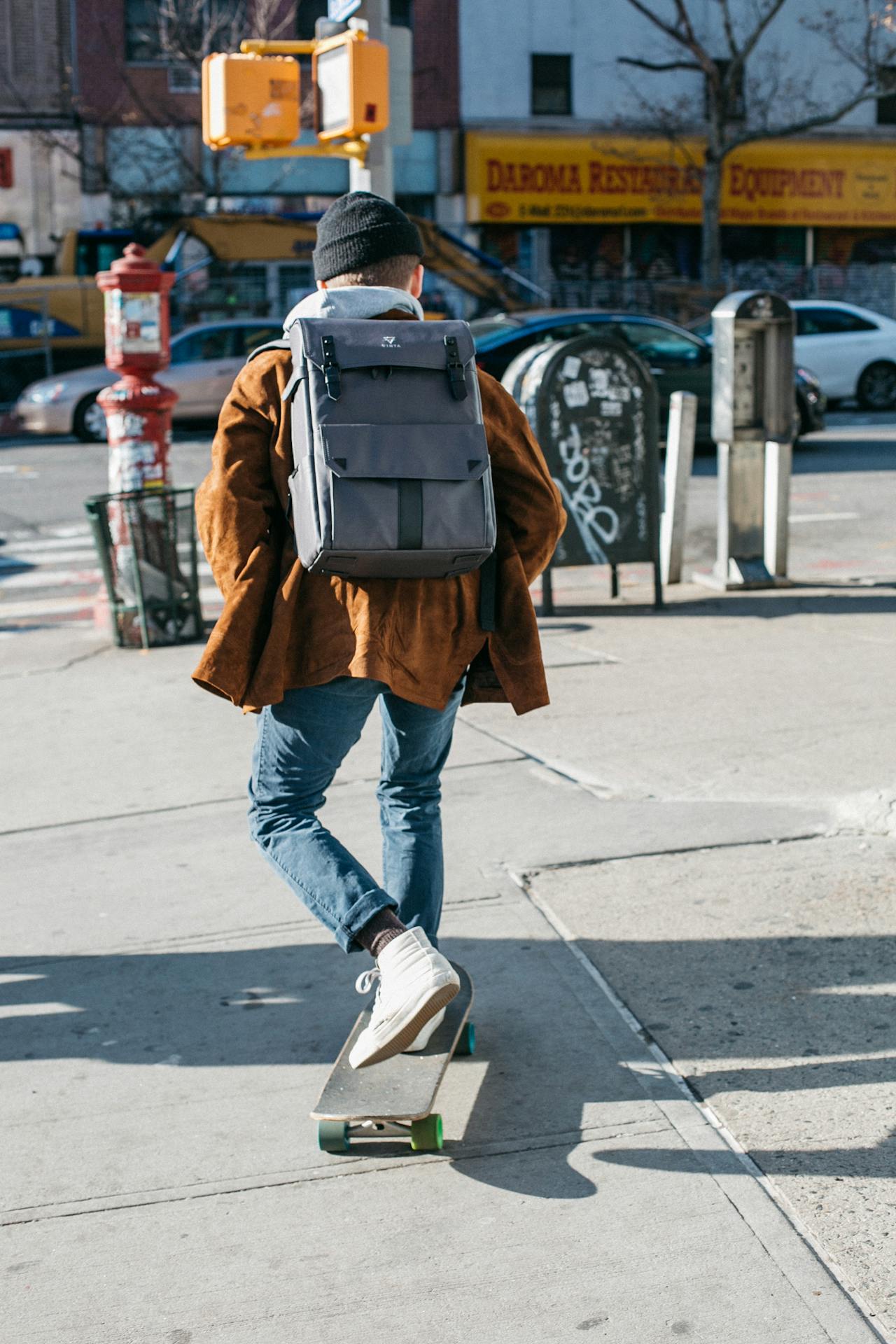 Man Wearing Brown Jacket, Blue Denim Jeans, and White Shoes Riding Skateboard